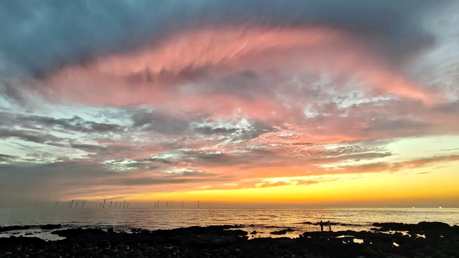 Sunset sky above the sea with distant turbines